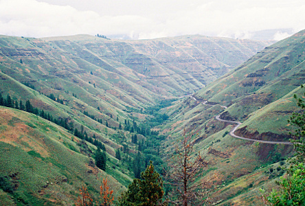 [Road cut into mountain side and it curves in and out with the mountain.]